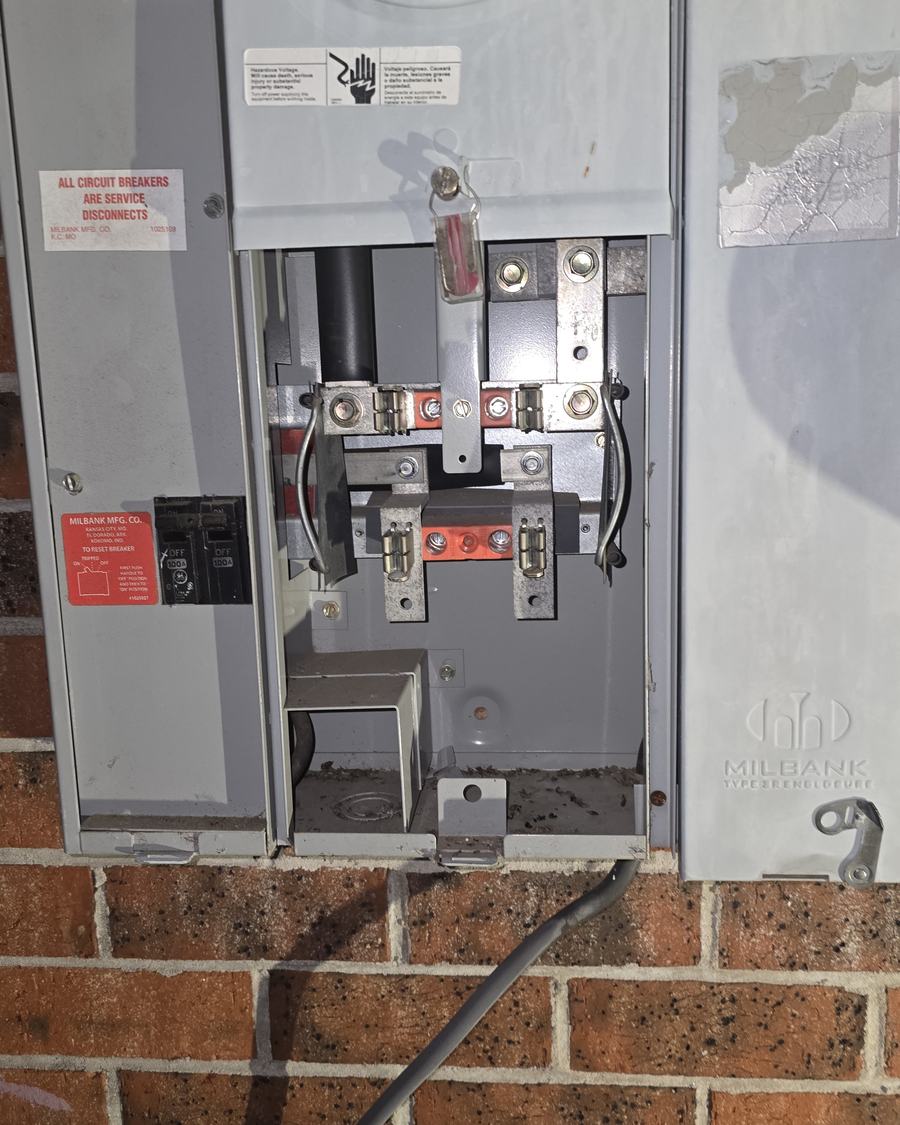 A meter base opened up on a brick wall