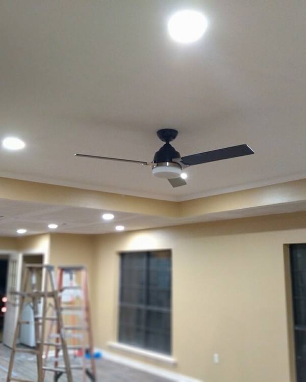 A room mid-remodel with new recessed lights and a ceiling fan