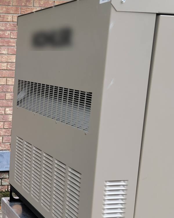 A standby generator on a pad beside a brick house