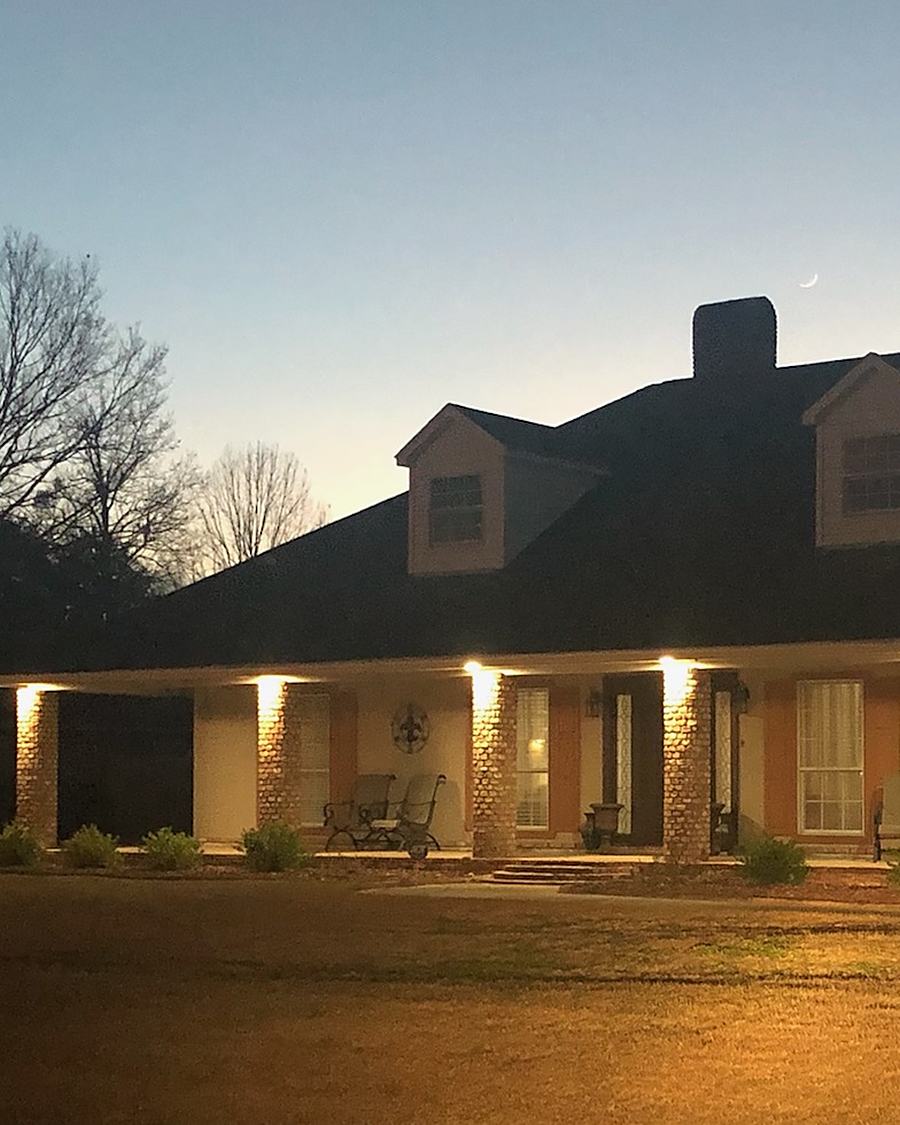 A brick house at dusk with soffit lights along the roofline