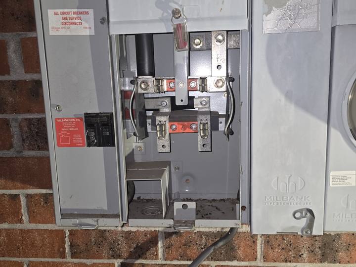 A meter base opened up on a brick wall