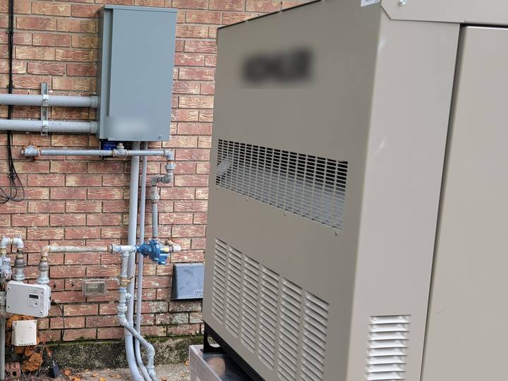 A standby generator beside an AC unit on a brick wall